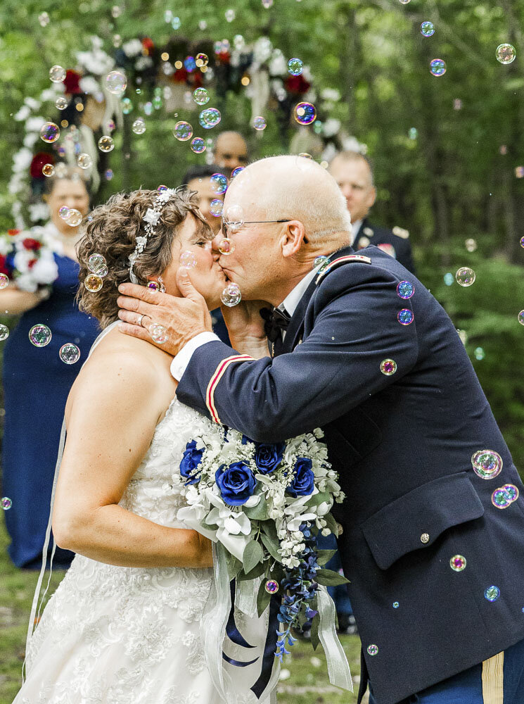 Groom kissing his bride as guests blow bubbles