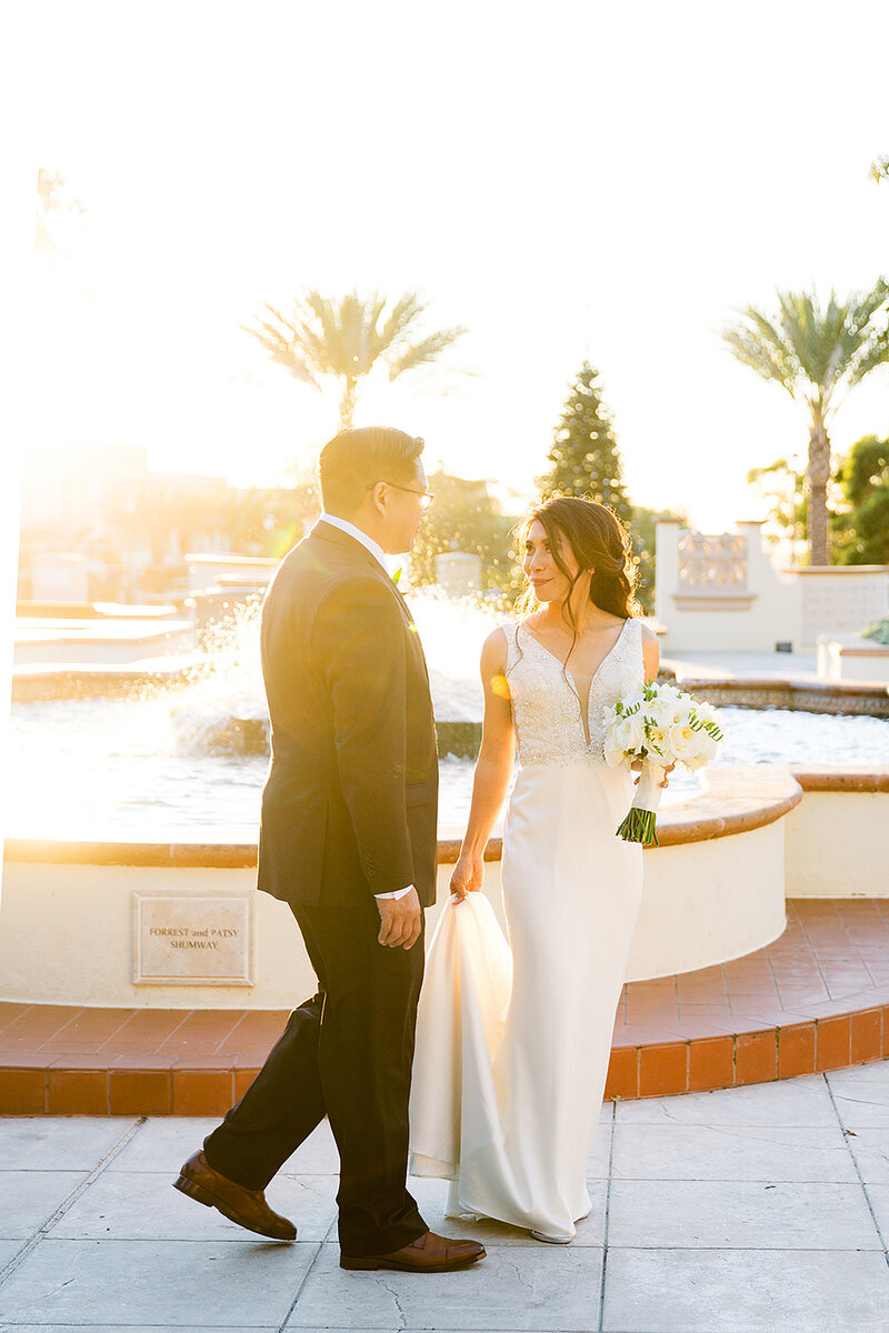 5-radiant-love-events-groom-looking-at-bride-in-front-of-water-fountain-with-golden-glare-of-sun-on-left-romantic-elegant-timeless