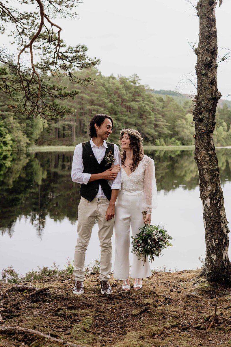 A couple stand hand in hand by the loch at Glen Tanar.