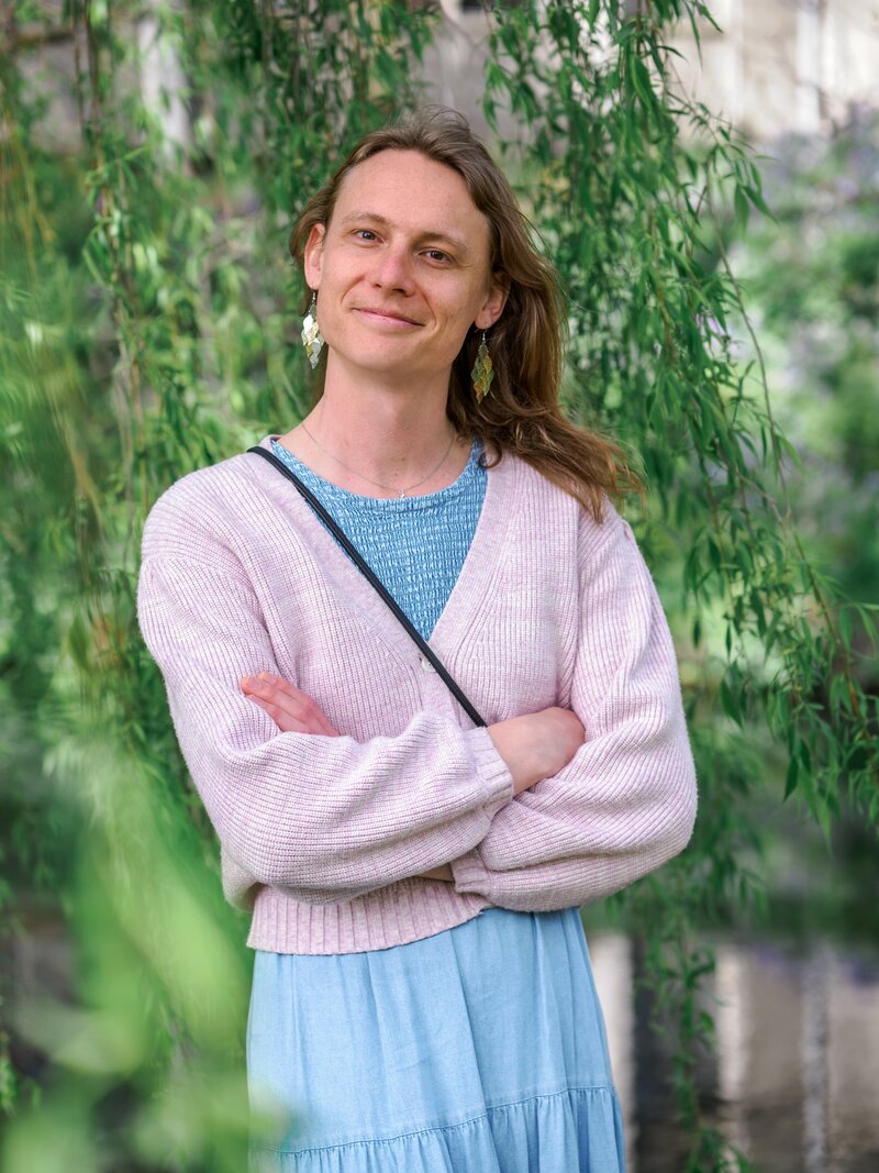 portrait of a trans woman standing in front of a willow tree in Christchurch Botanic Gardens