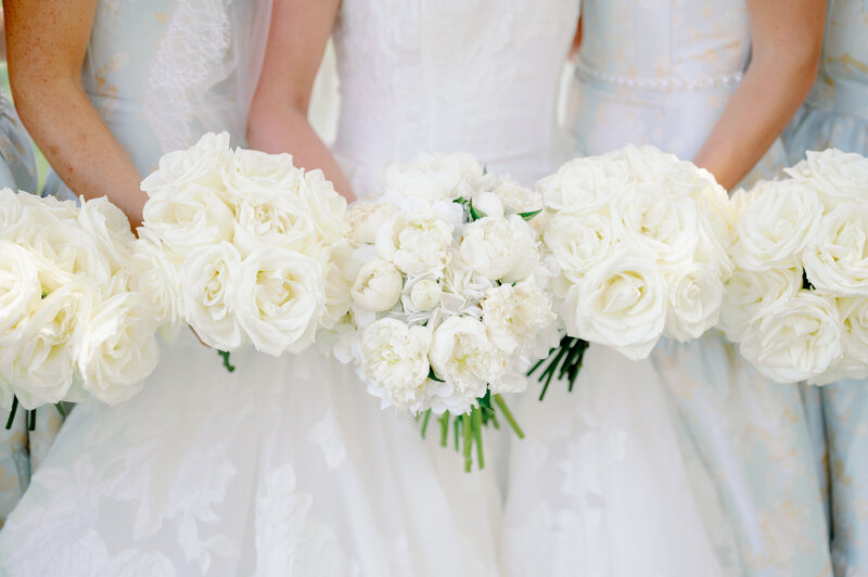 bride and bridesmaids in white dresses holding white flower bouquets