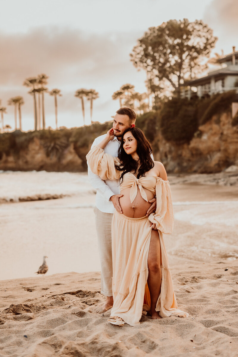 Pregnant couple during golden hour maternity session in Laguna Beach, California, captured by Southern California family photographer Brittani Luce