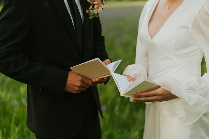 Wedding and elopement photography in Rexburg, Idaho by Adriana Montoya Photo. A close up detail shot of a bride and groom holding or reading out of their vow books. The photo is from the neck down.