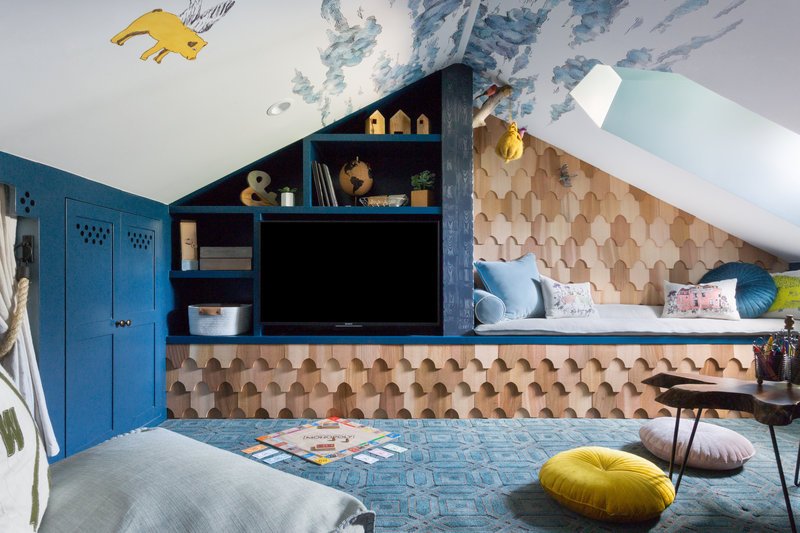 Attic playroom built in media cabinet, reading bench and storage, cedar shingled wall, cloud wallpaper with flying pig