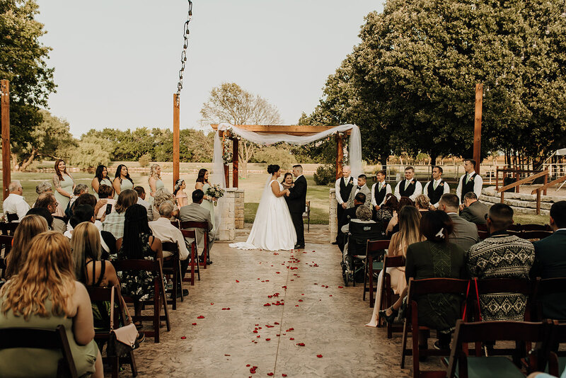 Bride and groom holding hands and giving vows during wedding ceremony