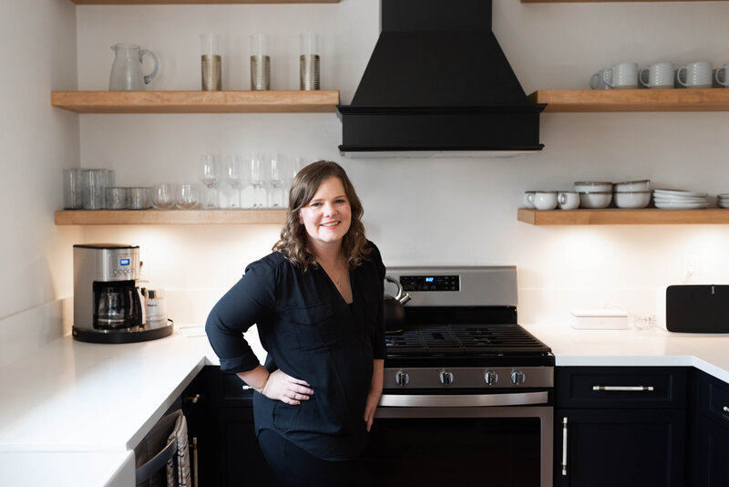 Santa Barbara County Realtor, Lindsey Drewes, smiles for photo in modern kitchen in black blouse