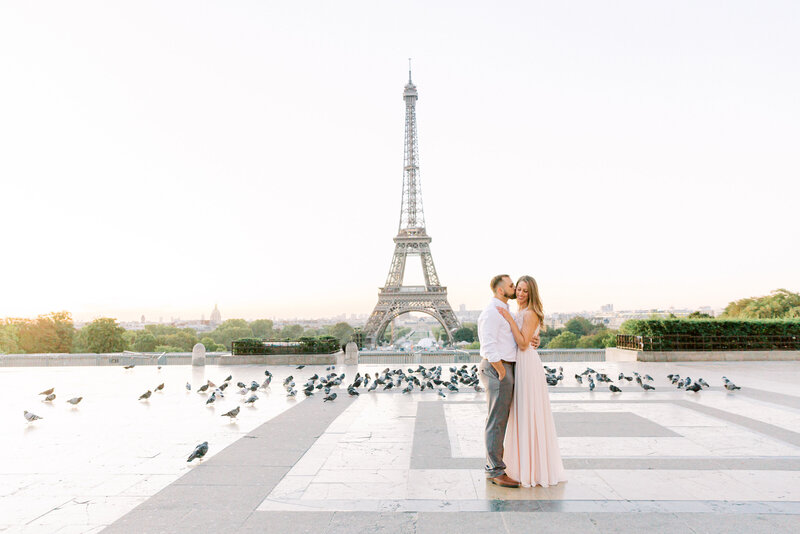 Danielle's husband kissing her on the cheek in front of the Eiffel Tower
