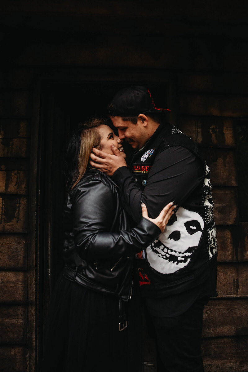Unique and alternative couple embraces at haunted house engagement session