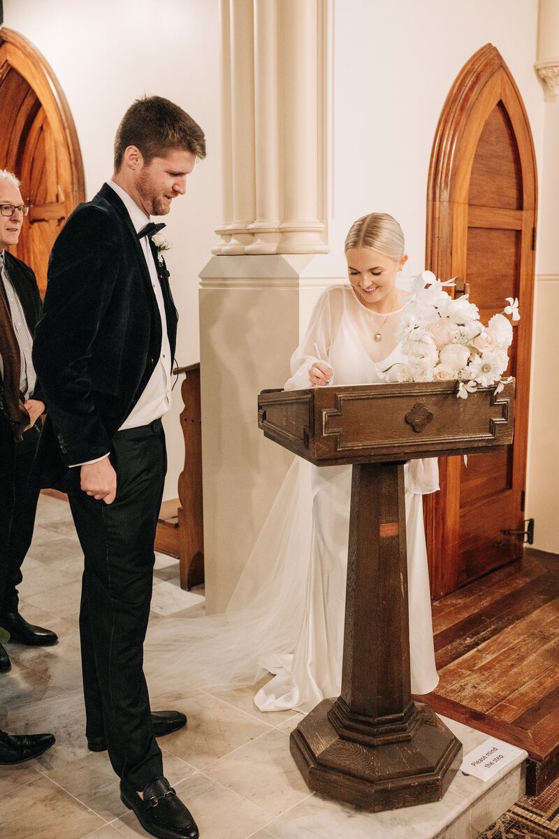 bride with white flower press chch bouquet signs register in the rose historic chapel christchurch