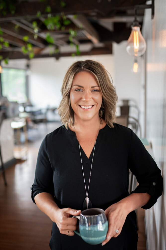 jen heller in a black shirt holding a coffee mug