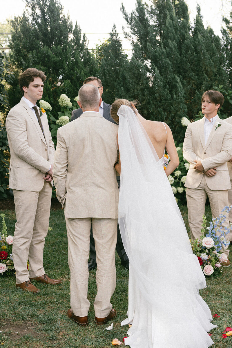 Bride leans her head on her fathers shoulder as they reach the alter on her wedding day.