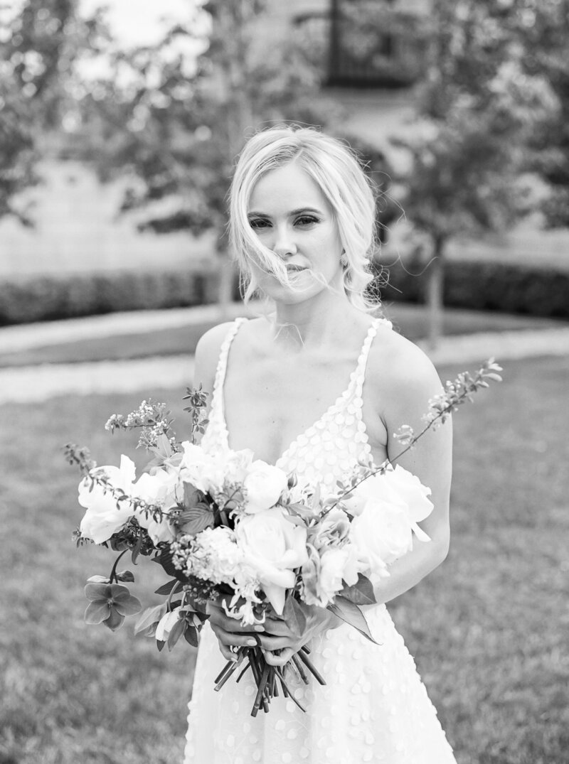 Black and white image of a blonde bride holding a white bouquet
