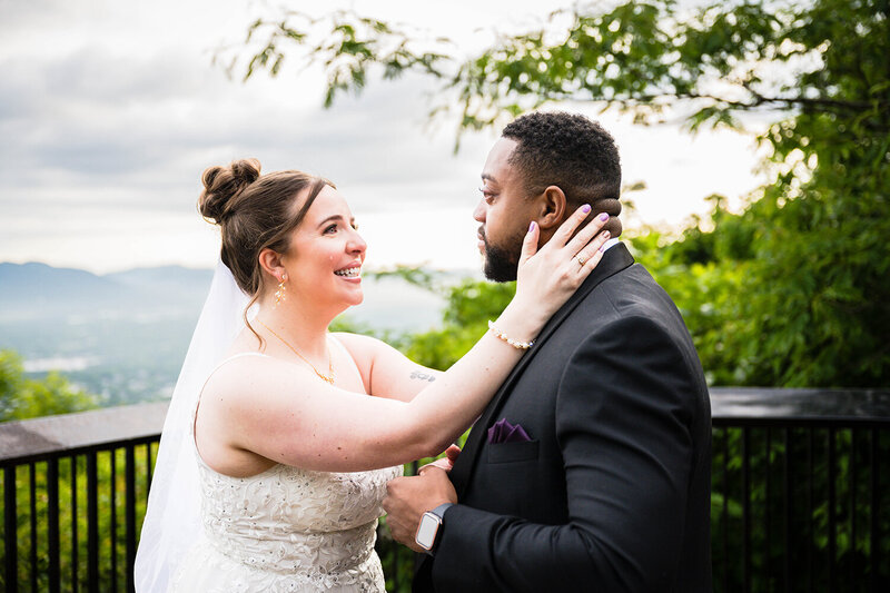 A bride holds onto her partner's face and sheds a single tear. Her face radiates with joy and excitement as they conclude their ceremony. The groom freezes and looks out emotionally at the view beyond them.