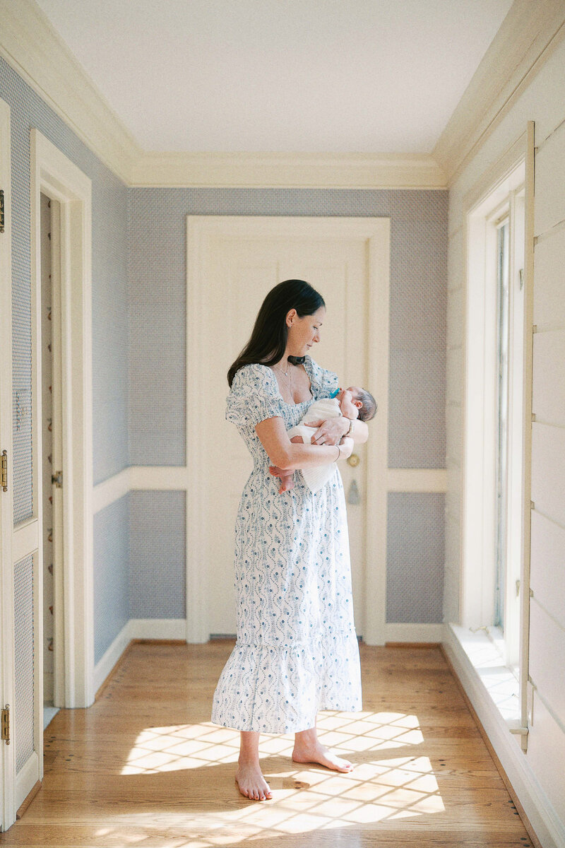 mom rocking baby in the hallway sunlight