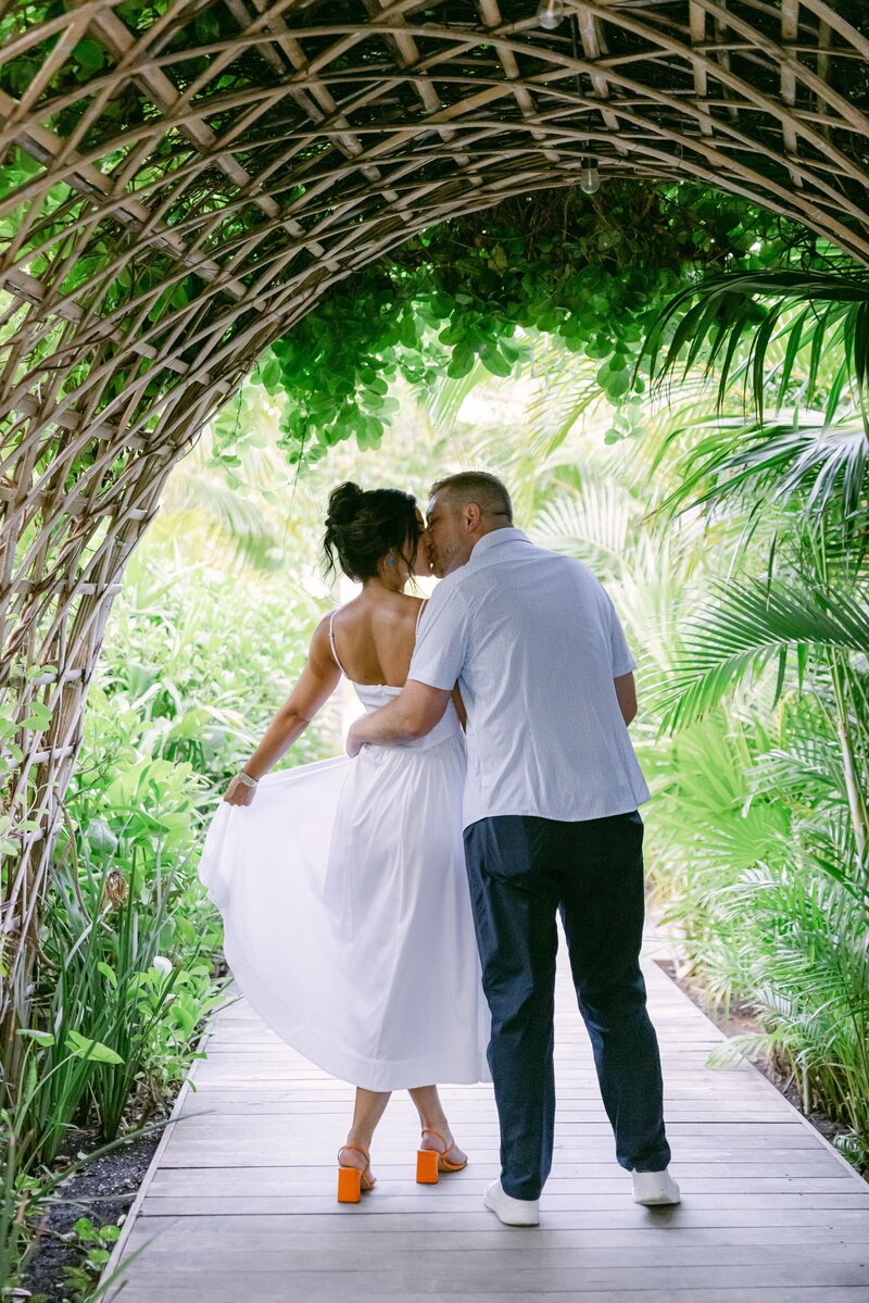 Couple walking through a tropical archway surrounded by lush greenery during their destination wedding or honeymoon