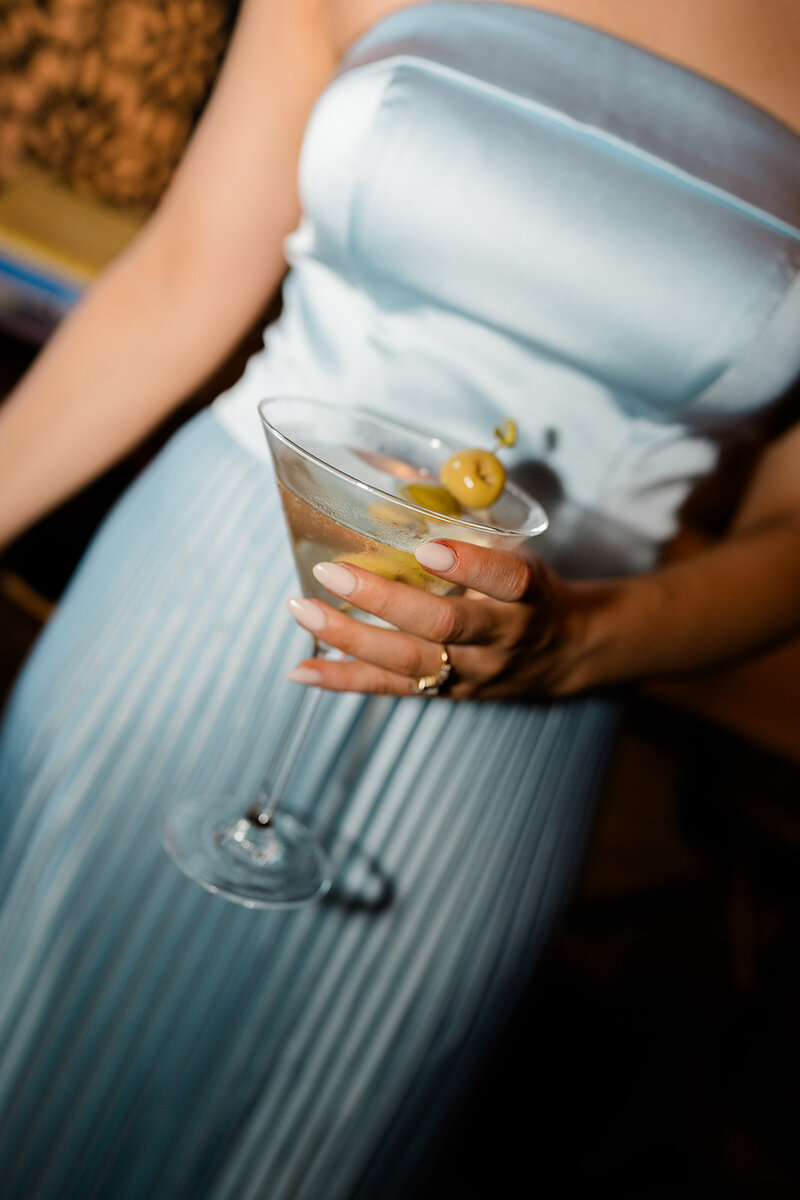 Flash photo of wedding guest holding a martini at cocktail hour at a wedding in New Jersey.