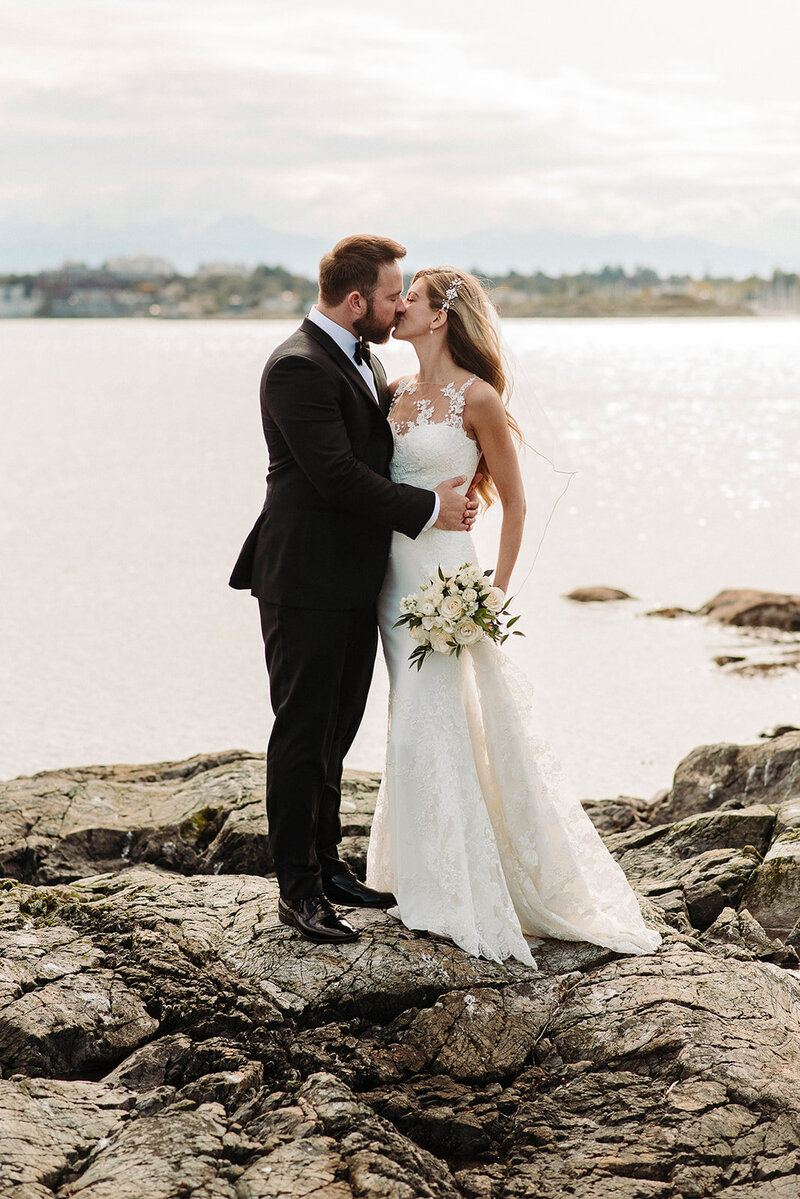 Bride and groom stand in snow in winter holding skis wearing heart shaped sunglasses