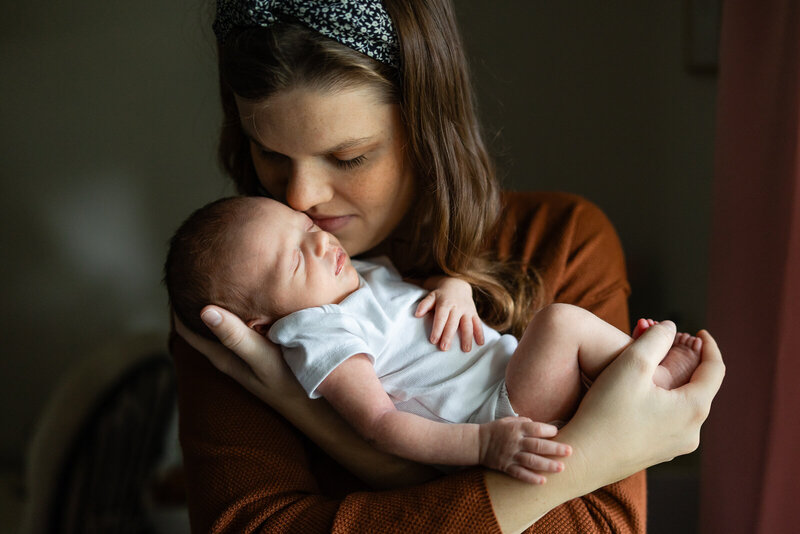 A natural light lifestyle portrait of an infant being held by her mother.