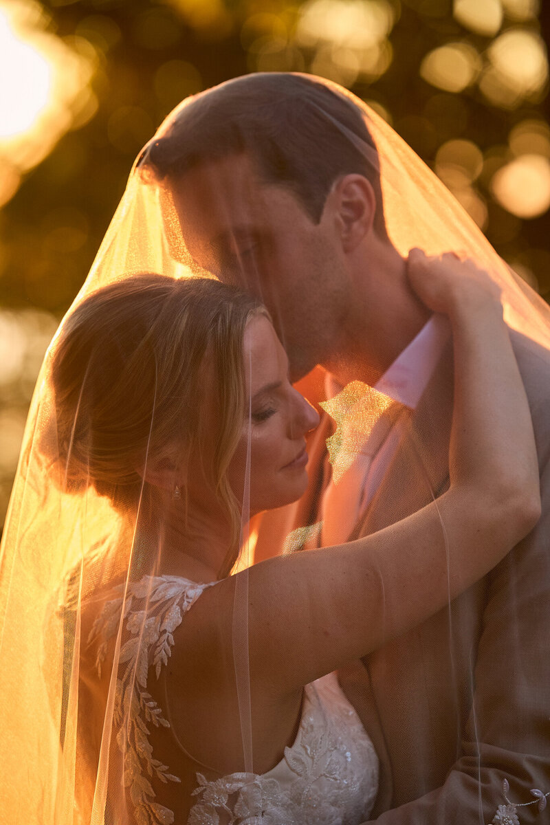 A bride with her wedding veil over her head and eyes closed