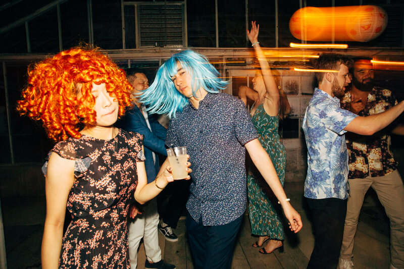 Guests in wigs showcase their dance moves in a candid photo by wedding photographer Megan Lynn of My Sun and Stars Co.