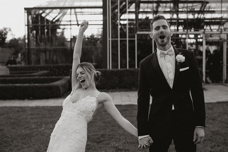 bride and groom cheering with joy holding hands