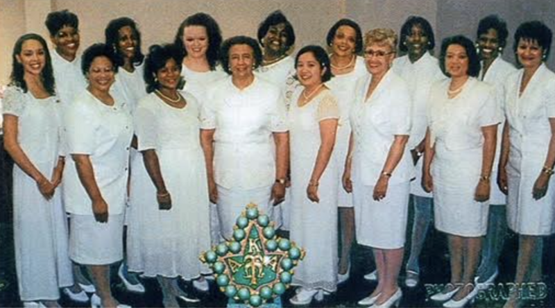 Phi Alpha Omega Charter Members and first initiating class wearing white and standing behind a giant green AKA pin
