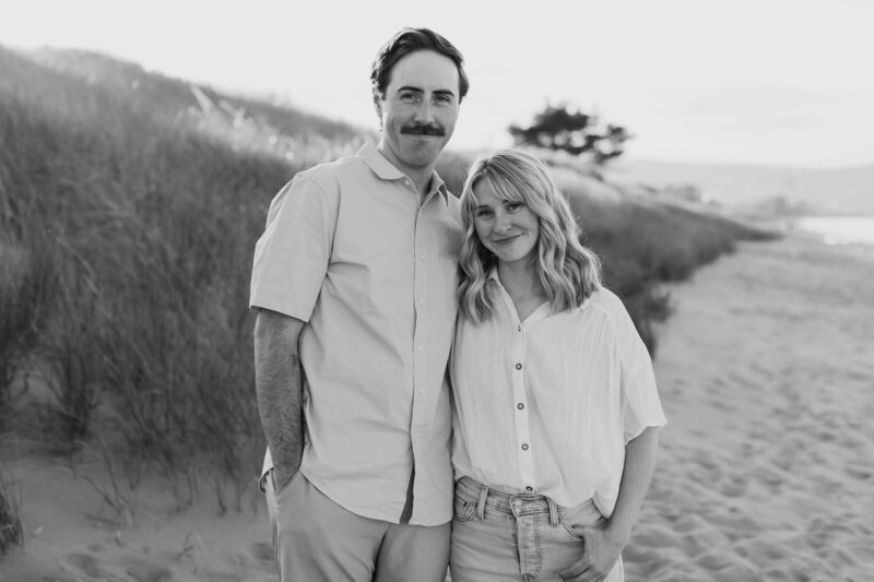 A couple with their arms around each other smiling at the beach 