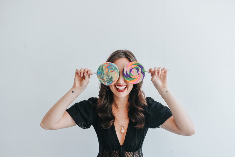 woman holding large lollipops over her eyes