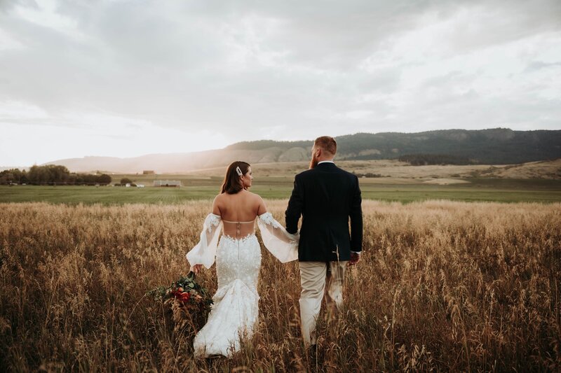 Wide shot of bride and groom in front of field