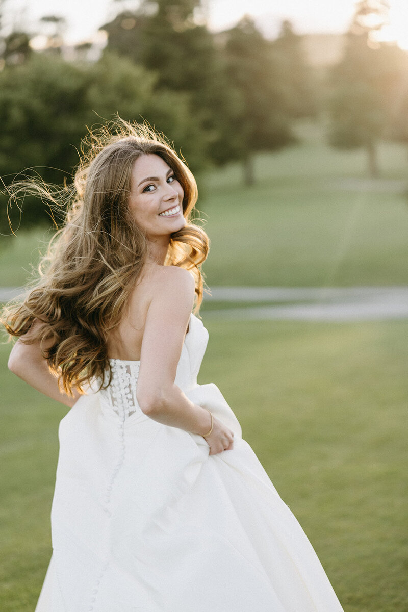 Bride smiling in strapless gown at golden hour