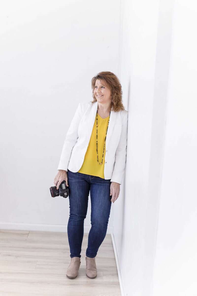 woman in yellow shirt leaning against wall