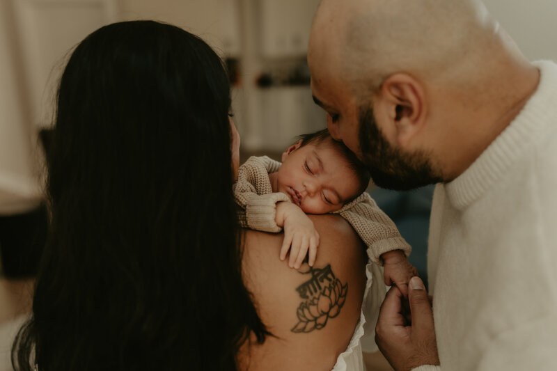 Newborn baby sleeping in a cozy knit outfit, gently cradled in a parent’s arms during a lifestyle newborn session in Metuchen, NJ, captured by Burkat Photography.