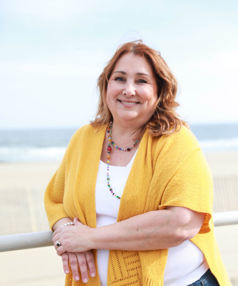 Kim standing in front of a railing next to the ocean