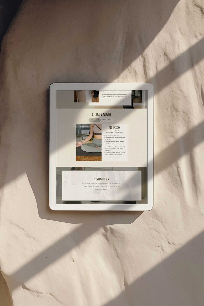 A tablet rests on a rock wall, showcasing the yoga studio design of Zenith Yoga and Pilates Studio's new website.