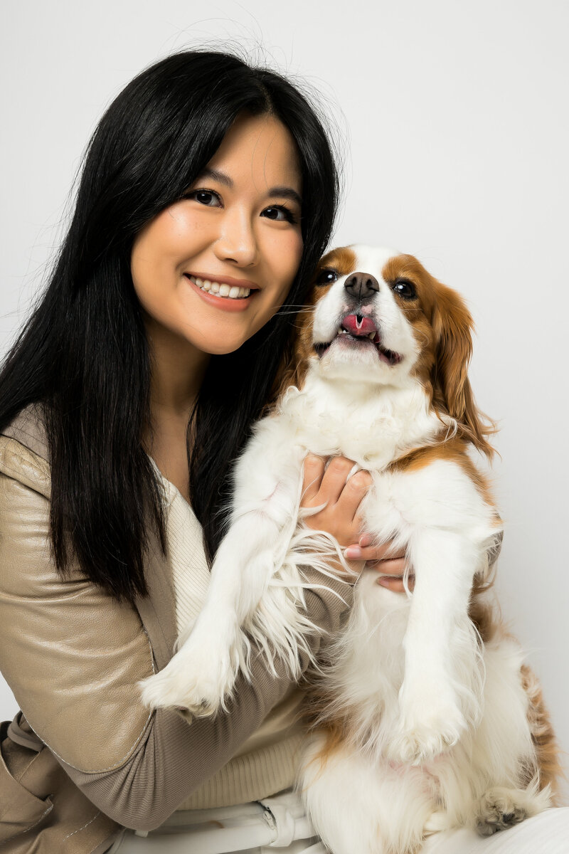 woman and cavalier king dog smile at camera in portrait studio