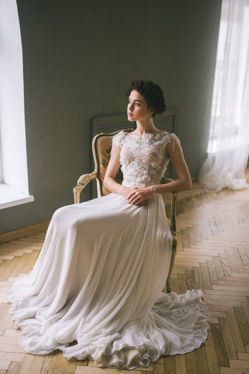 Elegant bride sitting on a chair. Portrait with her gown getting ready in a French Chateau in Bordeaux