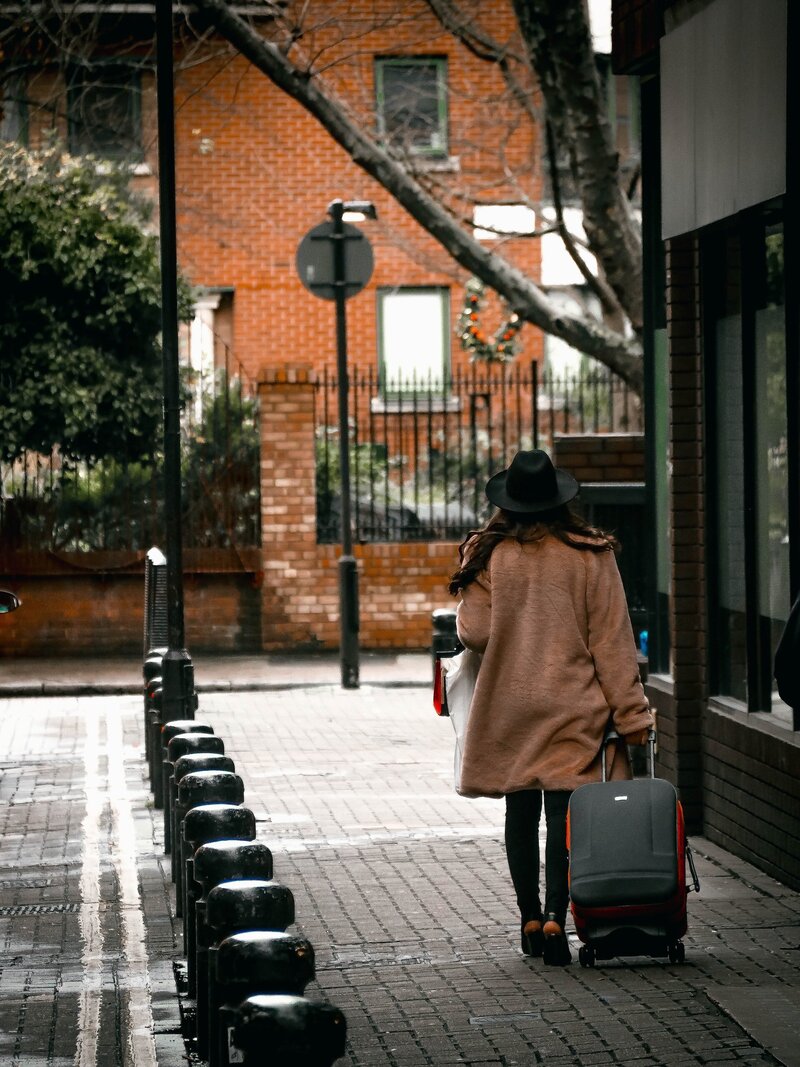 Woman walking on city street with suitecase_pexels-jacek-herbut
