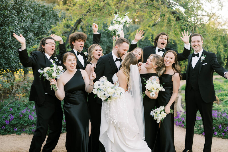 Bride and groom kissing with their reception and guests in the background