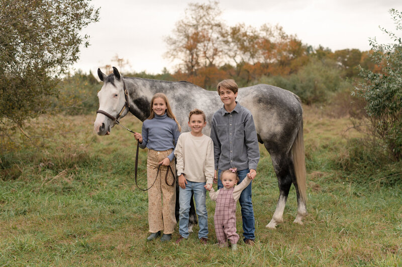 kids standing in front of grey horse