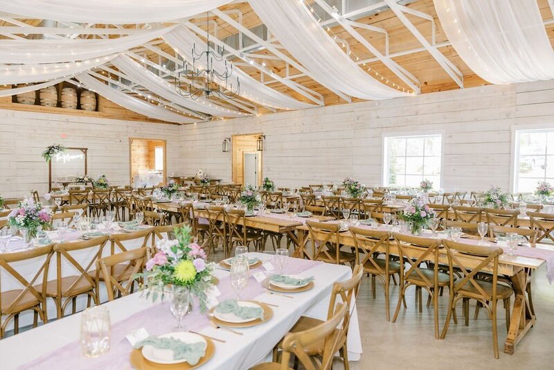 Wedding reception set up in white barn with fairy lights