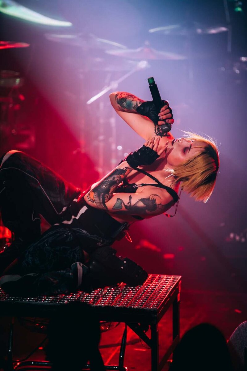 Mimi Barks sings to the sky on stage whilst crouching