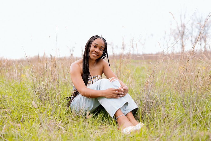 girl poses in field for senior photos in kansas city missouri