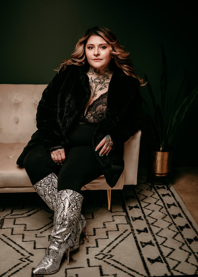 woman in studio sitting on white bench wearing black pants and black top