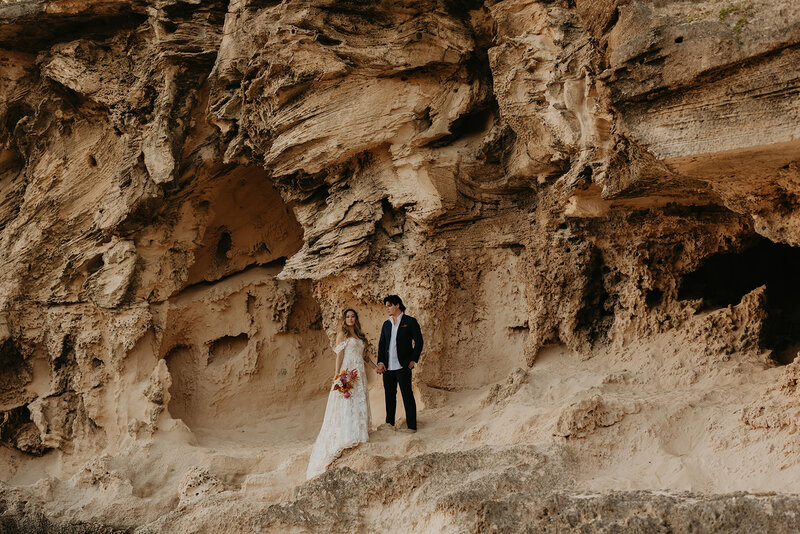 bride and groom standing on a cliffside