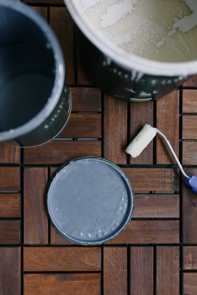 open paint container with roller frame and dark wood background