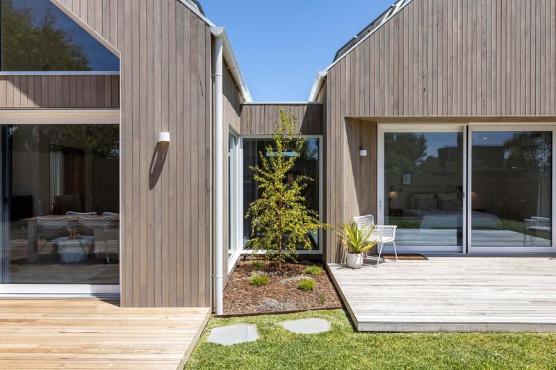 Timber cladded home with large windows and greenery on in the garden