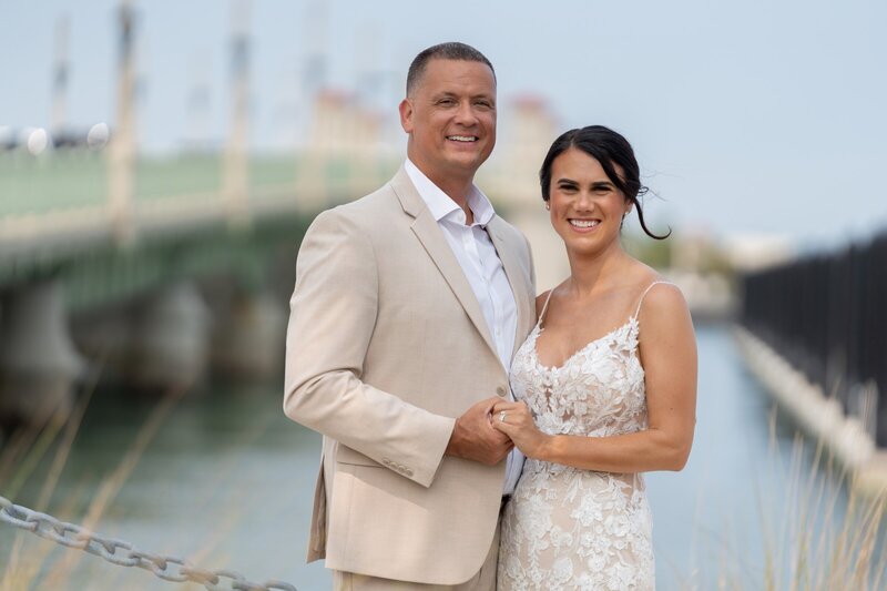 Happy couple posing at St Augustine marina during their waterfront elopement with the bridge of lions in background