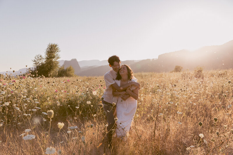Engaged couple runs through the wild flowers at their engagement shoot in the Columbia River Gorge.