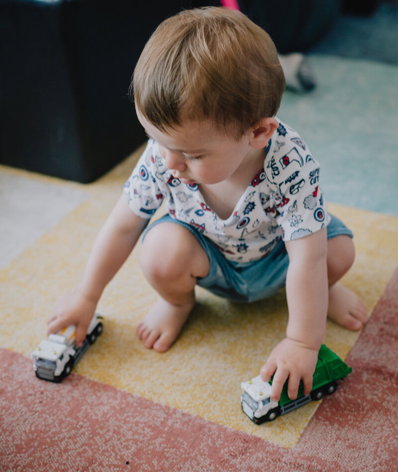 small-child-squats-and-plays-with-toy-trucks