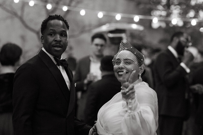 black and white photo of bride and groom bride giving peace sign at wedding reception in the city